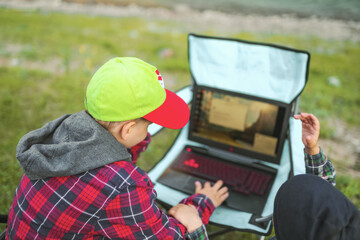 children using laptop outdoors .