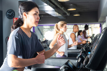 Portrait of young adult woman exercising on treadmill in gym
