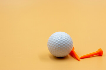 Golf ball with tee are on pale orange background