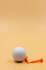 Golf ball with tee are on pale orange background