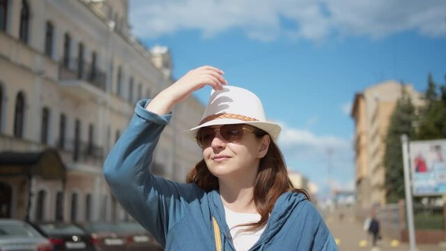 happy woman travels around the city, woman in a white hat walking through the city