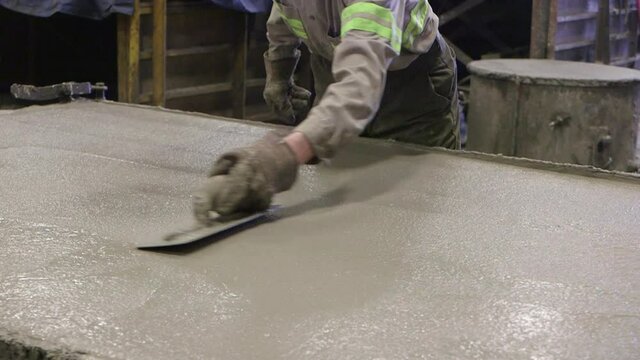 A man smooths-over a large area of concrete with a trowl - factory setting