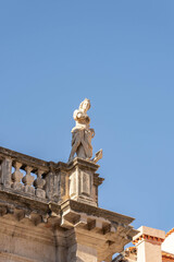 Fototapeta na wymiar Marble statue of goddess on top of building on stradun street in old town Dubrovnik in summer morning