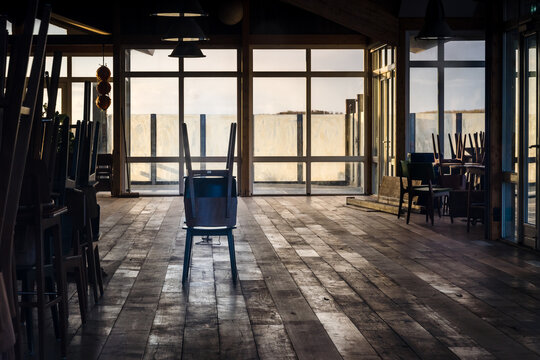 Empty Beach Pavilion With Stacked Wooden Tables And Chairs And Big Windows