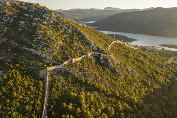 Aerial drone shot of City Wall of Ston over hill to Mali Ston in Croatia summer morning sunrise