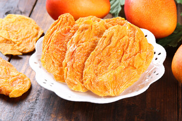 Dried Taiwan mango Dried Taiwan mango white plate on old wooden background.(mango candied)