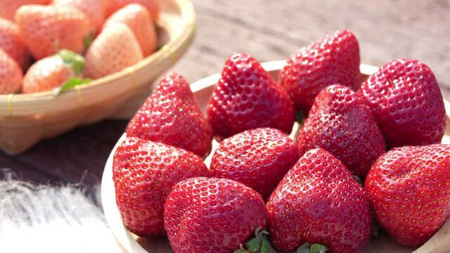 Fresh strawberries with leaves on bamboo basket, Red and White strawberry in Bamboo basket on wooden table.