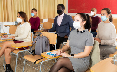 Group of adult students in protective masks at lecture at the university