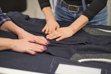 Obraz premium seamstress workplace. Woman seamstress makes pattern with chalk on fabric for sewing clothes in tailor studio. Tailor atelier handmade exclusive clothes making and repair. creative occupation concept