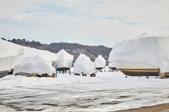 Boats wrapped and covered in white tarps along a river for the long and cold Minnesota winter