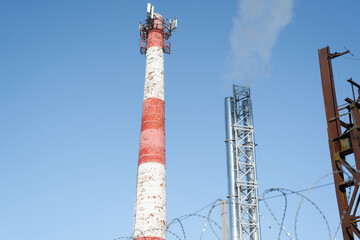 Tower with a pipe. Rising smoke into the clear light blue sky. Environmental pollution concept.