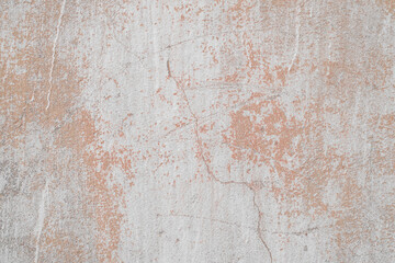 Texture of old concrete wall outside, close-up. Faded red paint, scratches, damage.