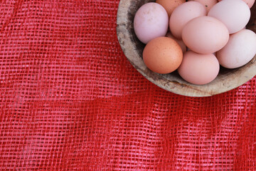 Eggs in the wooden bowl and red background, copy space for your text. 