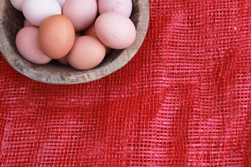 eggs in wooden bowl and red background, top view. Space for text.