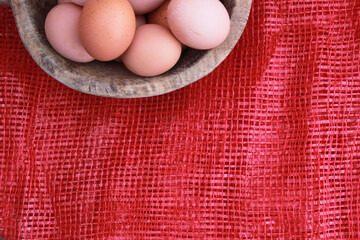 Eggs in the wooden bowl and red background for healthy, organic food. Copy space for your text. 