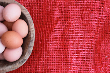 eggs in the wooden bowl and red nature background. Copy space for your text.