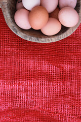 Eggs in the wooden bowl and red background for healthy, organic food. Copy space for your text. 