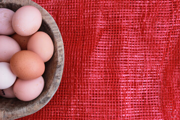 Eggs in the wooden bowl and red background for healthy, organic food. Copy space for your text. 