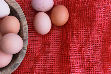 eggs in the wooden bowl and red nature background. Copy space for your text.