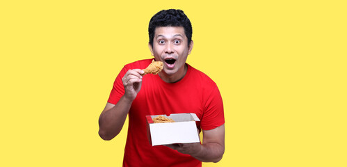 Asian man is eating fried chicken deliciously on Yellow background