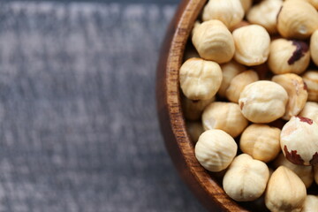 Hazelnuts peeled in a cup on a black shabby board background.top view. Healthy food and snack.
