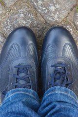 Comfortable navy blue leather shoes for men on road or footpath made of rocks or stones. Male footwear