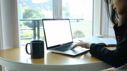 Fototapeta premium Close up view of businesswoman sitting near window and working on laptop computer.