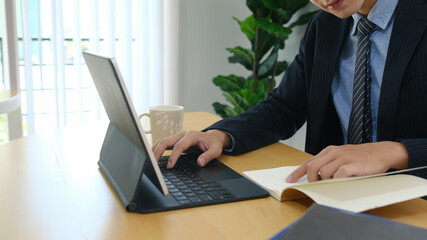 Cropped shot of businessman concentrate working on tablet computer at office desk.
