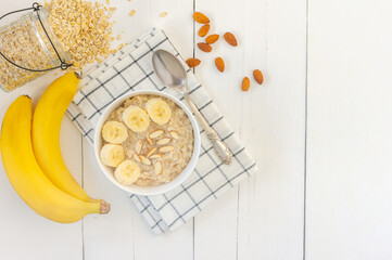 Top view of Bowl of oat flakes with sliced banana close-up on wooden table
