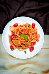 Tasty appetizing classic italian spaghetti pasta with tomato sauce and basil on plate on dark table. View from above, horizontal