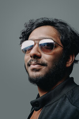 Obraz premium Bearded hindu with modern hairstyle and glasses. Closeup headshot of a cool guy he looks away in studio.