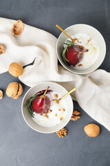 Bowls with sweet poached pears in red wine and ice-cream on dark background