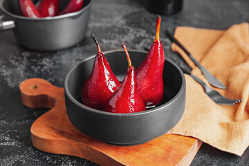 Bowl with sweet poached pears in red wine on dark background