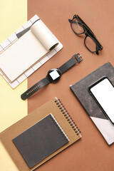 Modern smart watch with notebooks and glasses on color background
