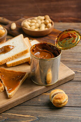 Tasty bread and boiled condensed milk on wooden background