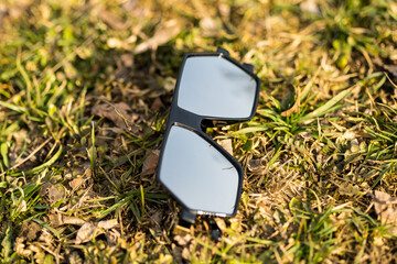 Futuristic oversized sunglasses model with silver color lenses shoot outdoor on grass in a sunny day closeup . Selective focus. High quality photo