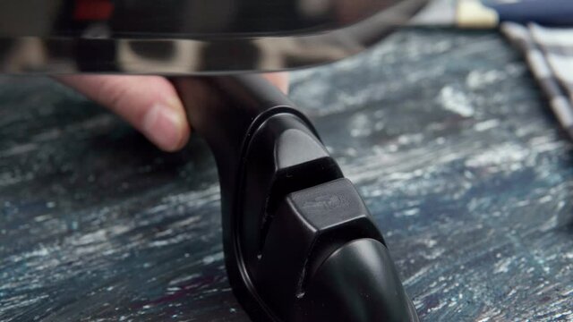 Sharpening a knife. Close-up of a man using a sharpener to sharpen a knife blade.