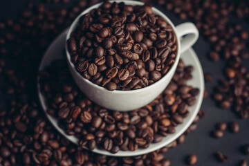 coffee beans in a cup and white saucers gray background close-up