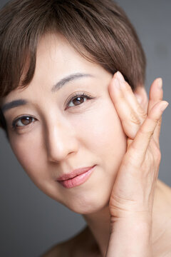 目尻を押さえながら微笑む中年の日本人女性