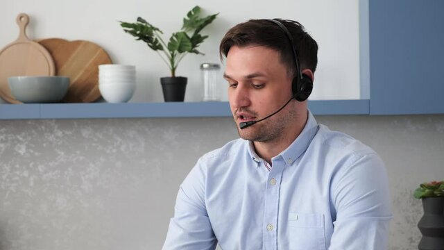 Closeup of young handsome call center agent wearing wireless headset earphones and microphone consulting at helpdesk Male technical support specialist doing e-commerce selling online. Customer service