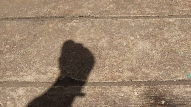 Shadow of open hand and fist for wrist exercise on cement flooring closeup.