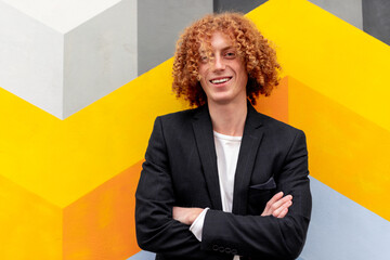 Positive guy with curly hair against colorful wall