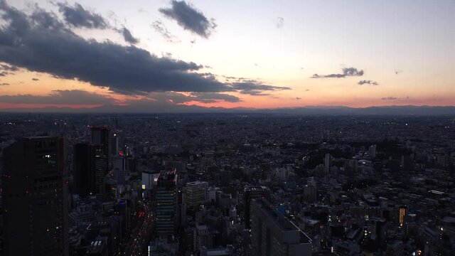 TOKYO, JAPAN : Aerial sunrise CITYSCAPE of TOKYO. View of rising sun and dramatic clouds around Shibuya. Japanese urban city life and nature concept. Long time lapse zoom out video, night to morning.
