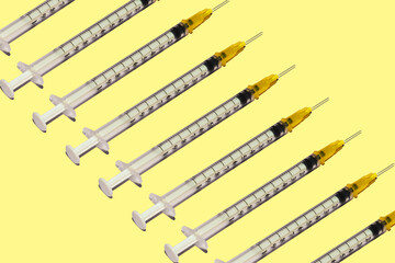 Pattern of medical syringes for vaccination against a virus on a yellow background