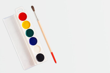 Palette of watercolor paints with a brush for painting on a white background copy space