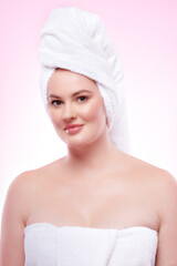 Beautiful woman wrapped in towels after spa treatment on pink background