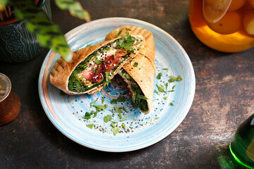 
Falafel in pita bread. Vegetarian street food. Tasty colorful healthy dish served on a background of green plants. Suggestion to serve the dish. Culinary photography.