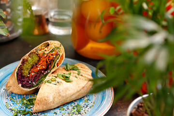 Vegetarian kebab, falafel with vegetables in pita bread.
A healthy vegan diet.
Tasty colorful healthy dish served on a background of green plants. Suggestion to serve the dish. Culinary photography.