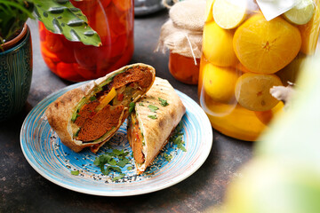 Vegetarian kebab, falafel with vegetables in pita bread.
A healthy vegan diet.
Tasty colorful healthy dish served on a background of green plants. Suggestion to serve the dish. Culinary photography.