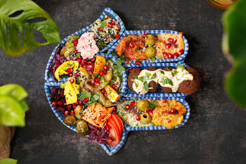 Obraz na płótnie Canvas Falafel with vegetables, a colorful vegetarian dish. A healthy vegan diet. Tasty colorful healthy dish served on a background of green plants. Suggestion to serve the dish. Culinary photography.